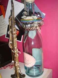 a glass bottle filled with jewelry sitting on top of a table