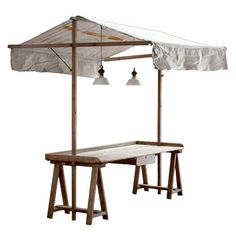 an outdoor table and umbrella set up on a white background with two bells hanging from the ceiling