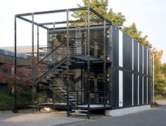 a large metal structure sitting on the side of a road next to a building with stairs