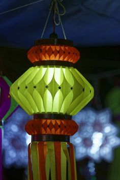 a colorful lamp hanging from a ceiling in a room with other lights and decorations behind it