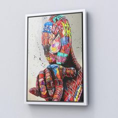 a painting of a person with colorful paint on it's face and hands, in front of a white wall