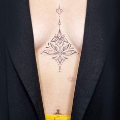 a woman's chest with a tattoo design on her left side, and a yellow belt around her waist