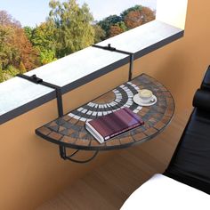 a table with a book on it next to a chair and window overlooking the trees