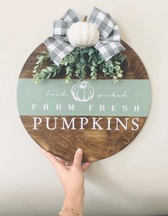 a hand holding a wooden sign that says farm fresh pumpkins