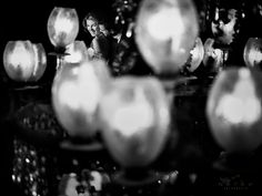 a black and white photo of candles in the dark with a man looking at them