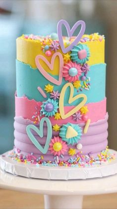 a multi - colored cake decorated with flowers and hearts