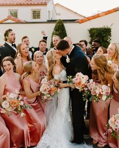 a bride and groom kissing surrounded by their bridal party