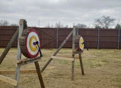 two wooden target stands in the middle of a yard with an arrow on each one