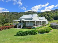 a white house sitting in the middle of a lush green field with trees and bushes