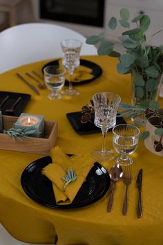 a yellow table cloth with black plates and silverware