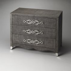 a gray dresser with three drawers and white trimmings on the top, against a grey background