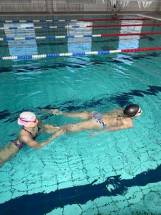 a woman swimming in a pool wearing a pink hat