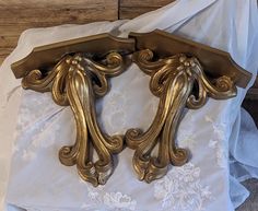 two ornate gold brackets on a white sheet