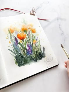 someone is painting flowers with watercolors on paper