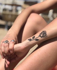 two women sitting on the ground with tattoos on their legs and one has a rose tattooed on her arm