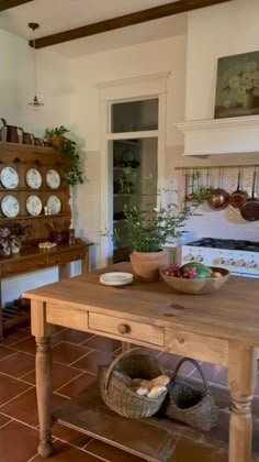 a wooden table sitting in the middle of a kitchen next to a stove top oven