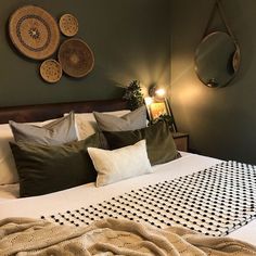 a bed with lots of pillows on top of it next to a wall mounted mirror