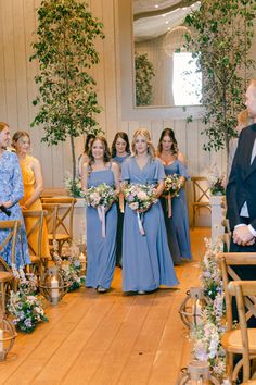 a group of people standing next to each other in front of a wooden floored room