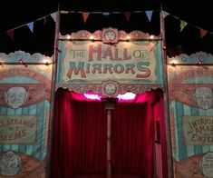 a stage set with red curtains and lights on the sides, in front of a sign that says the hall of mirrors