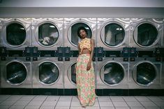 a woman standing in front of a row of washers with her hands on her hips