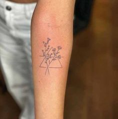 a woman's arm with a tattoo on it that has flowers in the center