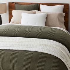 a bed with green and white bedspread next to two lamps on either side