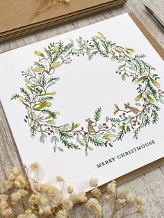 a christmas card with a wreath on it next to dried flowers and twine of twine