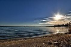 the sun shines brightly over an empty beach and body of water on a sunny day