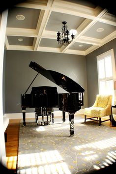 a living room with a grand piano in the center and two yellow chairs around it