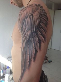 the back of a man's arm with an angel wing tattoo on his shoulder