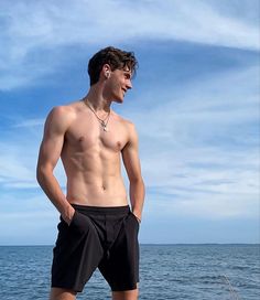 a shirtless man standing on the edge of a boat