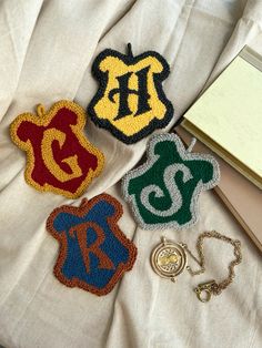 three harry potter inspired patches on a white blanket next to a book and keychain