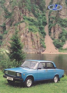 a blue car parked in front of a mountain