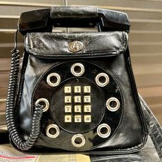 Unique Black Leather 70’s Vintage Phone Bag. Tested. Phone Still Works! Wear Throughout As Seen In Photos, But Quite A Piece Still! Strap Can Be Used As A Crossbody Or Shoulder Bag. Clasp Closure Inner Zipper Pocket Inner Pouch Pocket Bag Is 8 1/2” Tall With Receiver Is 11” Tall 9 1/2” Wide At Bottom 7” At Top About 2 1/2” Deep Smoke-Free And Golden Retriever-Friendly Household. 70s Accessories Purse, Dallas Core, Bag Clasp, Leather Phone Bag, Vintage Phone, Vintage Phones, Pocket Bag, Vintage Bags, Phone Bag