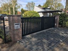 a brick fence with a black gate in front of it