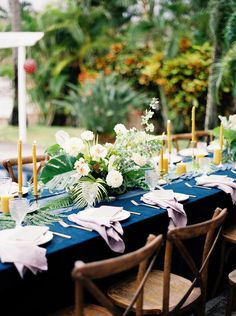 a long table is set up with flowers and candles for an outdoor wedding reception in the garden