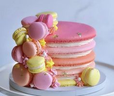 a stack of pink and yellow macaroons sitting on top of a white plate