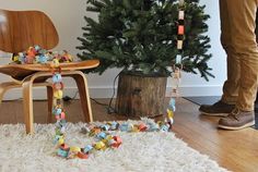 a man standing next to a christmas tree in a living room with decorations on the floor