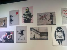 a bunch of pictures are hanging on the wall in front of a white wall with black and red images