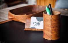 a desk with a pen holder and two pens in it on top of a table