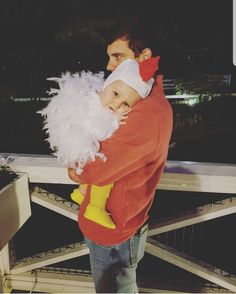 a man holding a baby in his arms and wearing a santa costume on top of him