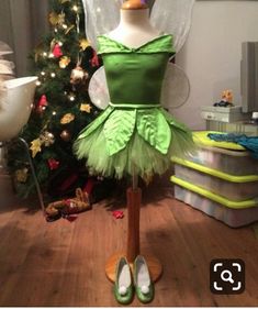 a green fairy costume on display in front of a christmas tree