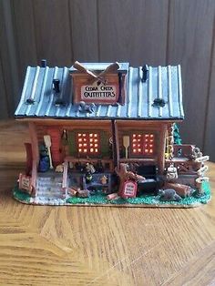 a small toy store with lights on and animals in the front yard, sitting on a wooden table