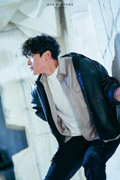 a young man is leaning against a wall