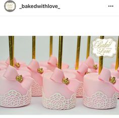 pink cupcakes with bows and gold toppers are lined up on a table