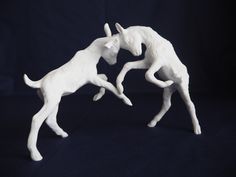 two white figurines are playing with each other on a black tablecloth background