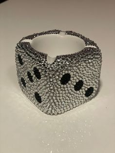 a beaded bracelet with black and white dots on the side, sitting on a table