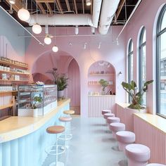 the interior of a pink and white cafe with stools in front of it,