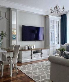 a living room filled with furniture and a flat screen tv mounted to the wall in front of a window