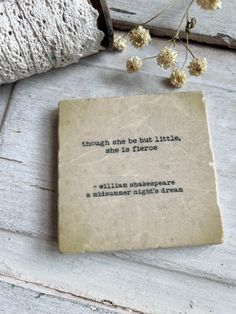 an old book sitting on top of a white wooden floor next to flowers and a roll of string